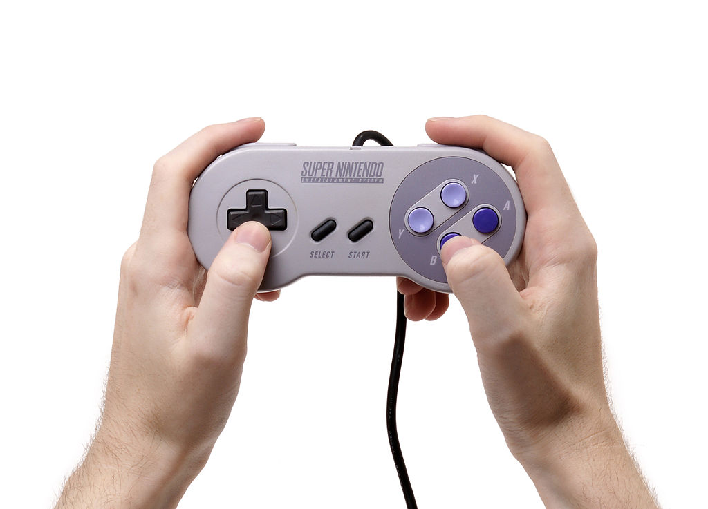 Gracz trzymający kontroler North American Super Nintendo Entertainment System - widoczne tylko dłonie i kontroler