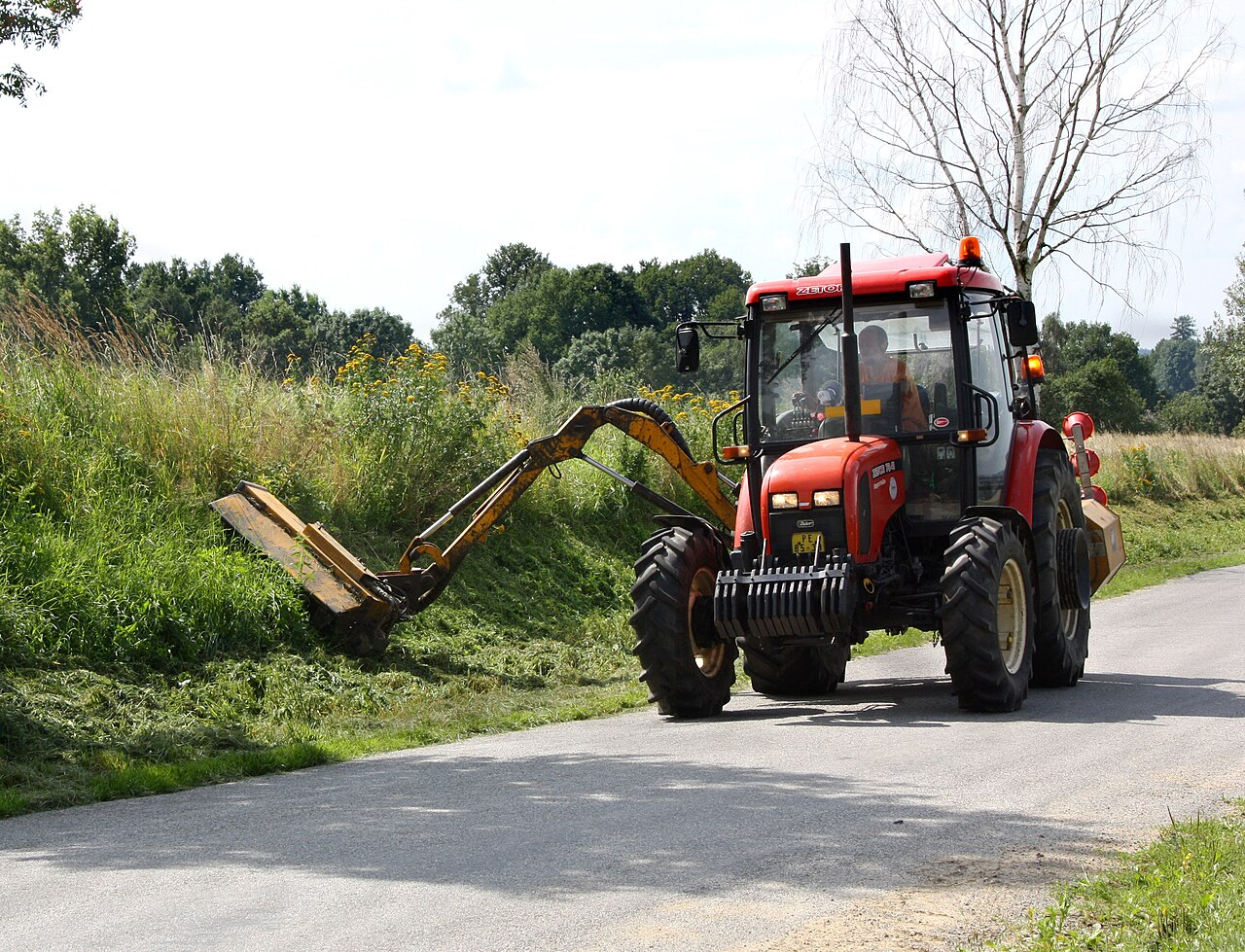 Kosiarka ciągnięta przez traktor z długim ramieniem